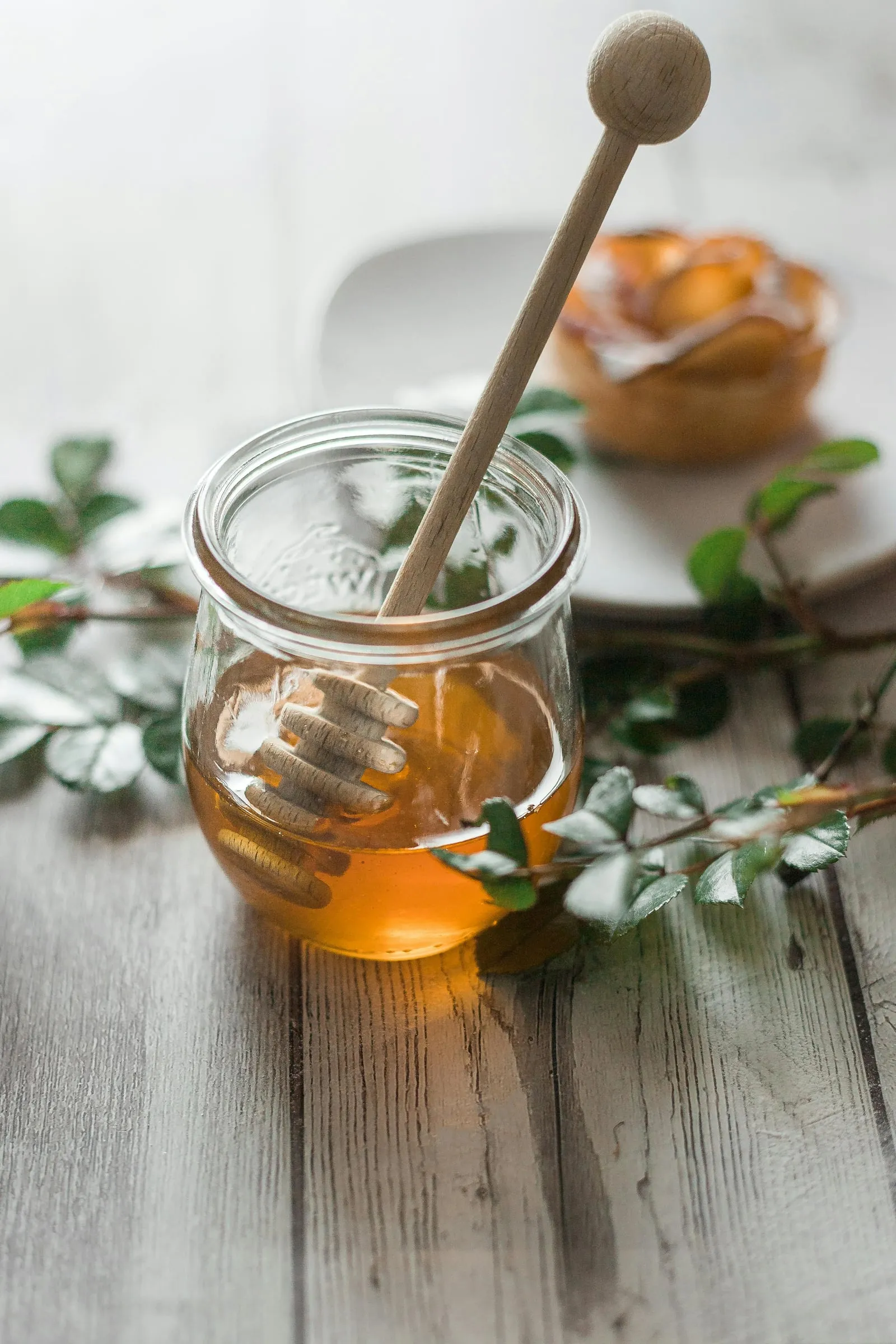 A jar of golden honey with a wooden dipper