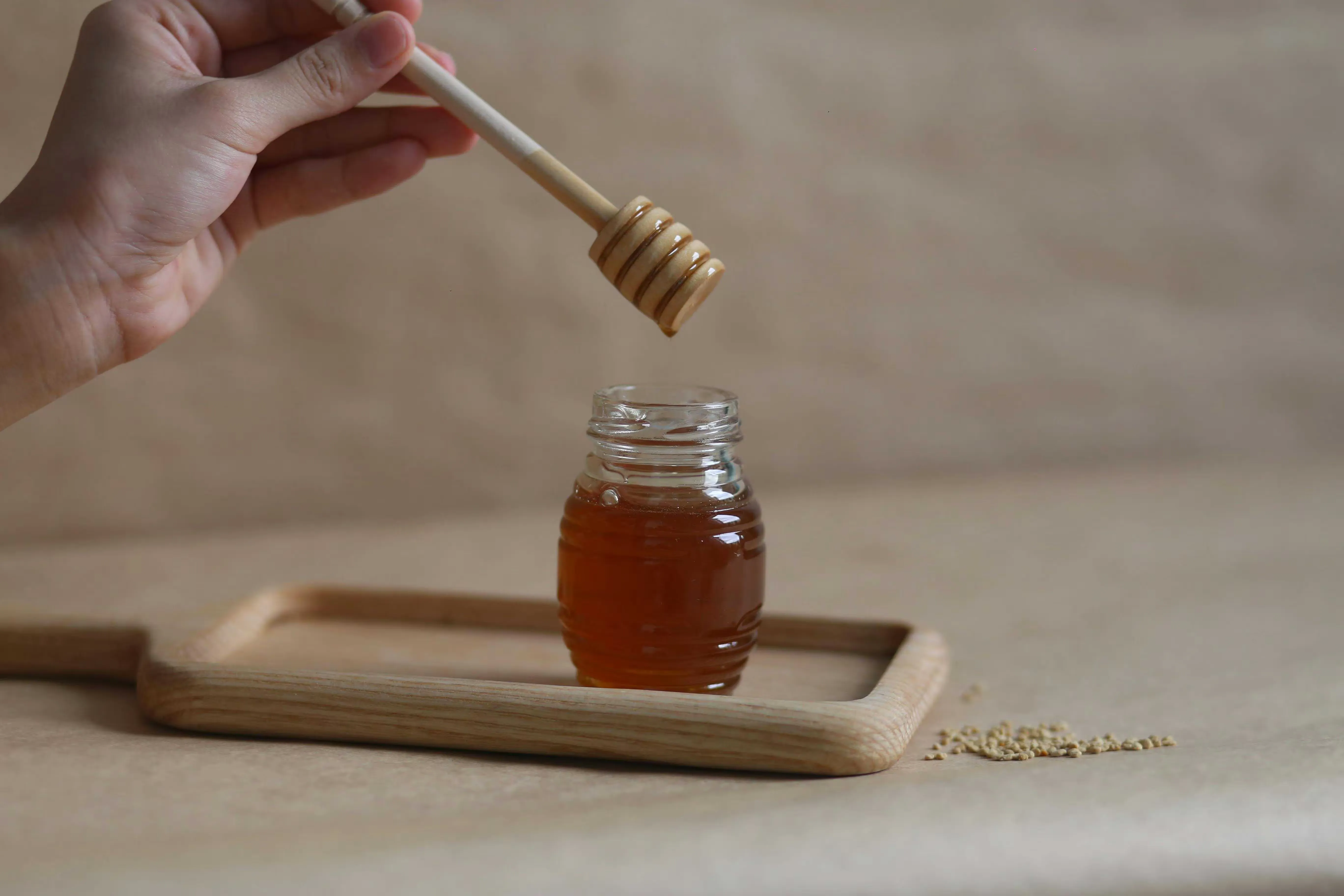 A small jar of honey with a wooden dipper