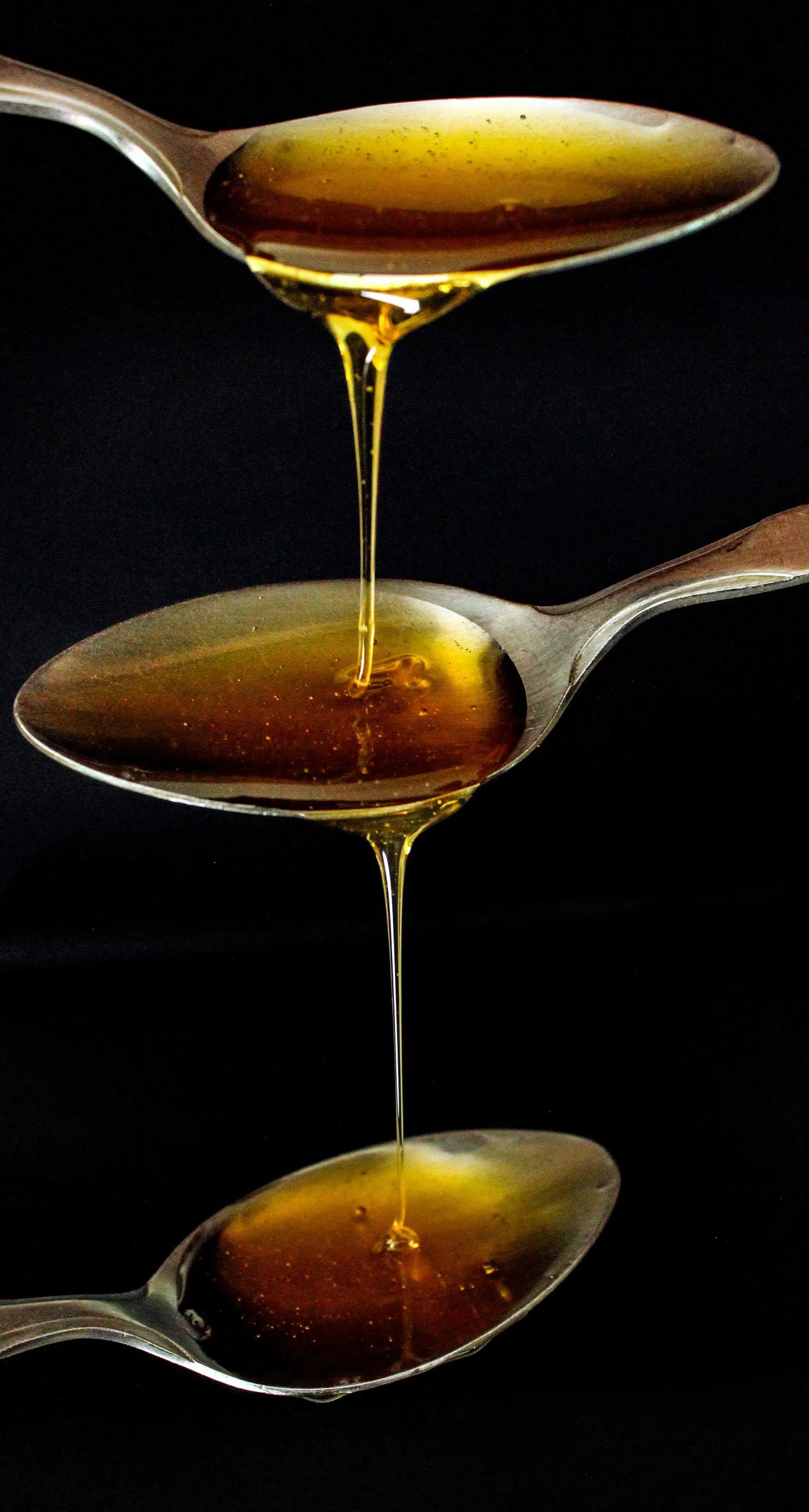 Dark honey pouring off a spoon
